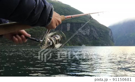 A fisherman pulls a trout out of the water on a spinning rod and